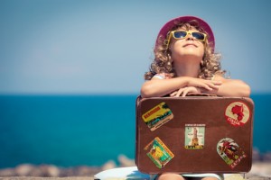 Child with vintage suitcase on summer vacation. Travel and adventure concept