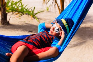 happy little boy relaxed in hammock on beach, family vacation